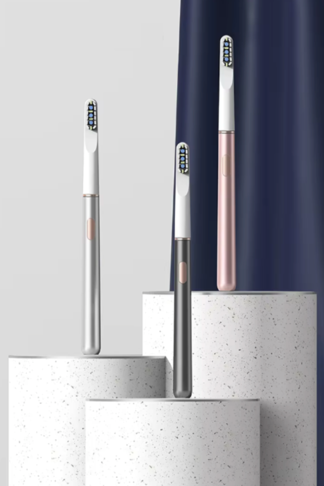 Three toothbrushes of different designs on cylindrical stands against a white background